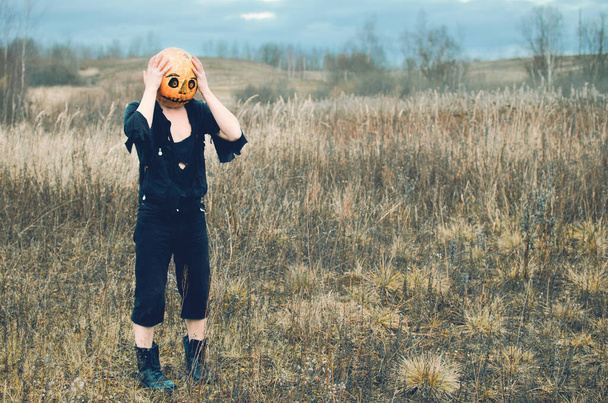 Хэллоуинское пугало с тыквой на голове, сжимающей голову на осеннем поле - Фото, изображение