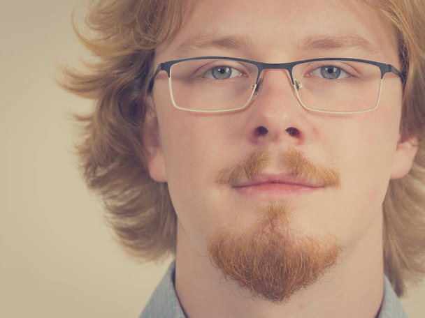 Cheerful funny looking nerdy guy with ginger hair and eyeglasses having beard. - Fotó, kép