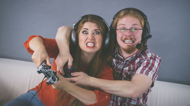 Пара наслаждается досугом, играя в видеоигры вместе, мужчина и женщина эмоциональны от игры. - Фото, изображение