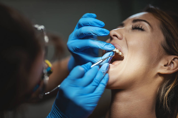 その美しい若い女性は歯医者にいる。歯医者の椅子に座り歯の上に歯を食いしばり. - 写真・画像