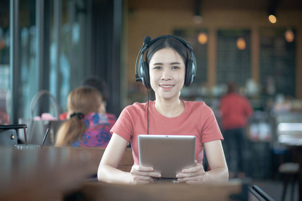Mujeres asiáticas usando tableta escuchando música sentada cafetería, concepto personas negocios tecnología estilo de vida - Foto, imagen