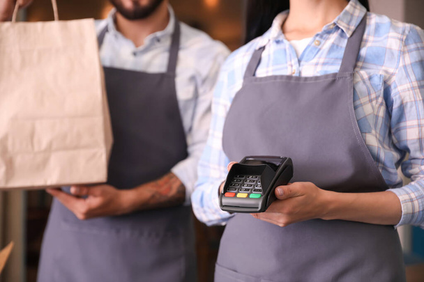Young waiters with food for delivery and payment terminal in restaurant - Foto, immagini