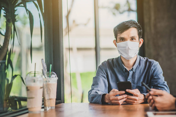 Ázsiai Man üzleti használni arc maszk ül kávézó életmód új normális társadalmi távolság lezárása után corona vírus - Fotó, kép
