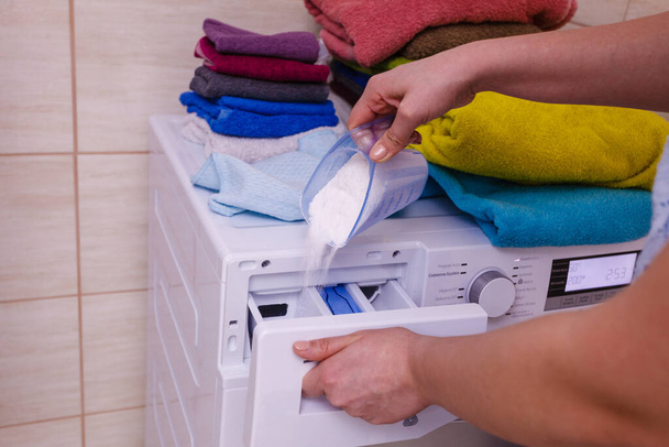 Female hand pour the washing powder detergent into machine. - Фото, изображение