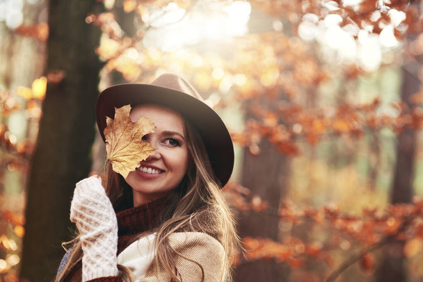 Happy beautiful woman  covering eye with autumnal leaves - Foto, Imagen