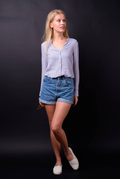 Studio shot of beautiful woman with blond hair wearing smart casual clothing against black background - Фото, изображение