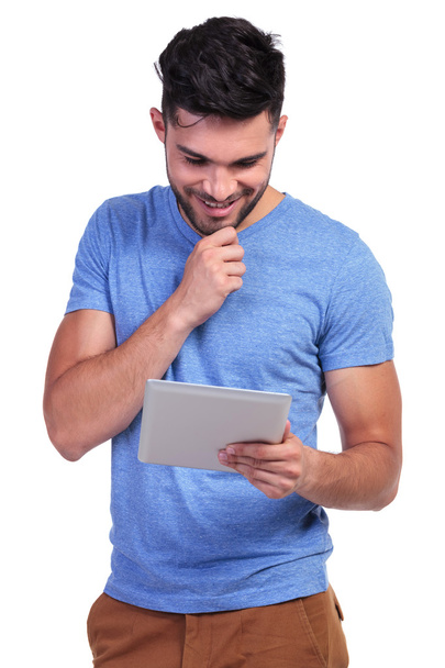 smiling man is reading interesting stuff on his tablet pad - Фото, изображение