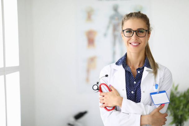 Female doctor in medical office is holding a stethoscope and smiling - Photo, image