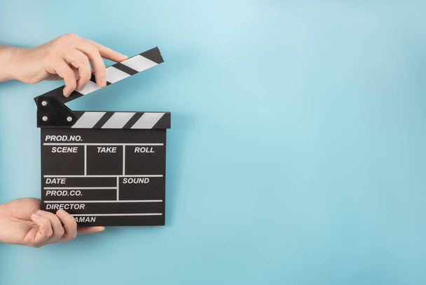 Movie clapperboard in hands on a blue background - Фото, изображение