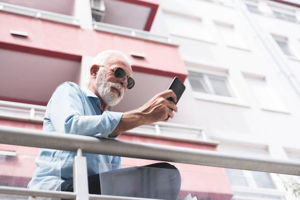 Ανώτερος άνθρωπος που χρησιμοποιεί το κινητό τηλέφωνο στην πόλη, έννοια της τεχνολογίας - Φωτογραφία, εικόνα