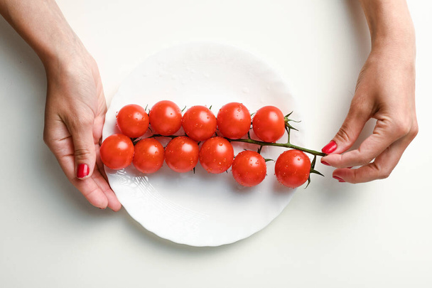 větev rajčat v ruce na bílém talíři. Kvalitní fotografie - Fotografie, Obrázek
