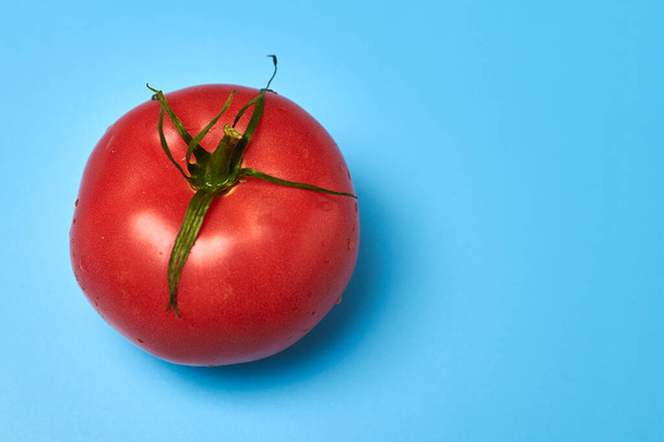 Whole appetizing red tomato on a blue background. - Фото, изображение