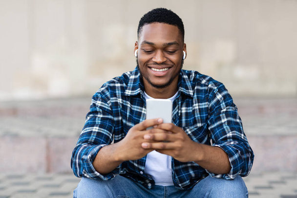 Portrait d'un gars écoutant de la musique et envoyant des SMS au téléphone - Photo, image