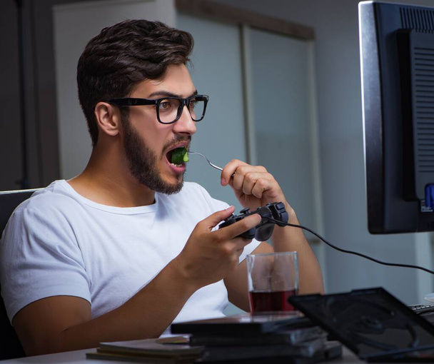 Молодий чоловік грає в ігри на довгі години пізно в офісі
 - Фото, зображення