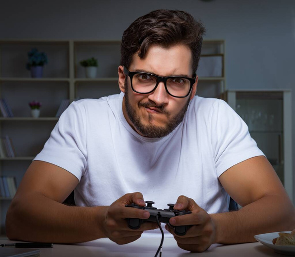 Mladý muž hraje hry dlouhé hodiny pozdě v kanceláři - Fotografie, Obrázek
