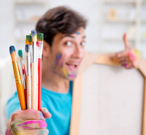 Молодой забавный художник работает над новой картиной в своей студии - Фото, изображение