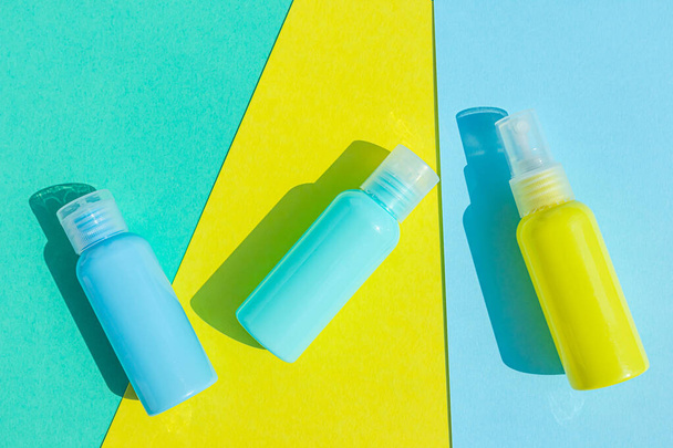 Yellow and blue cosmetic bottles on the same colored background. Stylish concept of organic essences, beauty and health products. Copy space, minimalism, flat lay. - Foto, Bild