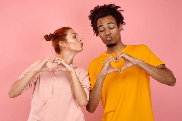 Young interracial couple with closed eyes showing hands a heart. - Fotoğraf, Görsel