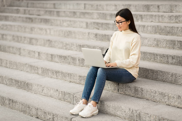 Женщина в очках с ноутбуком, сидит на лестнице - Фото, изображение