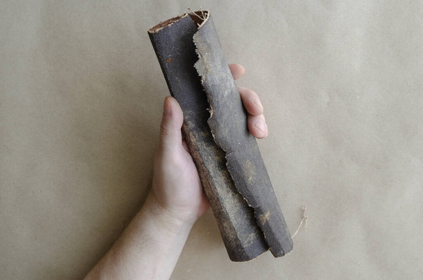 Caucasian man is holding an old sandpaper. The hand of a middle-aged man with a scroll of used sandpaper. Manual labor. Selective focus. - Photo, Image
