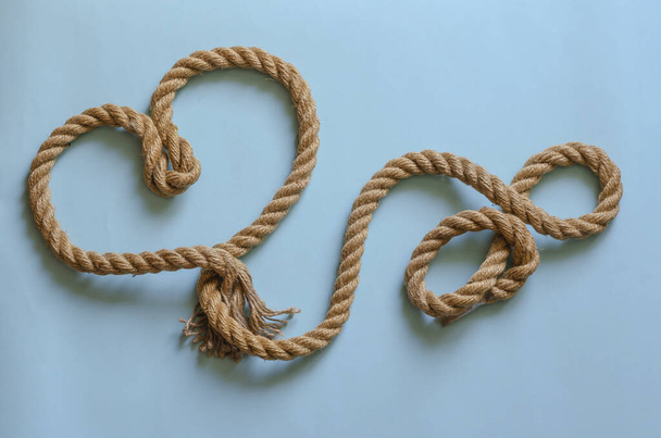 Symbol of a loving heart made of hemp rope. Thick cable laid out in the shape of a heart. Valentine's day background. Top view at an angle. - Фото, изображение