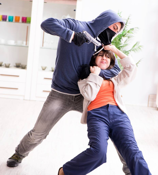 Hombre armado agrediendo a una joven en casa - Foto, imagen