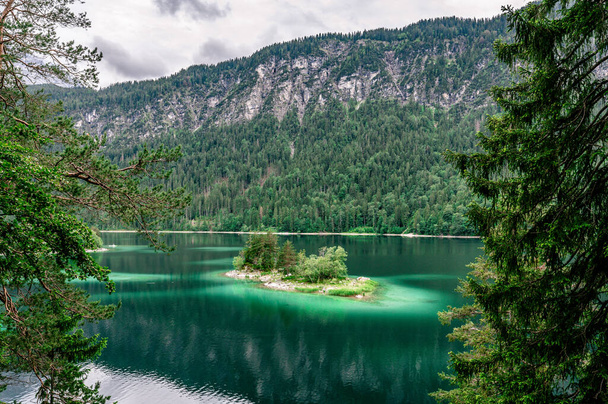 Small islands with pine-trees in the middle of Eibsee lake with Zugspitze mountain. Beautiful landscape scenery with paradise beach and clear blue water in German Alps, Bavaria, Germany, Europe. - 写真・画像