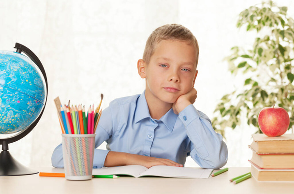 Young schoolboy sitting at the table and doing homework. Elementary education concept - Photo, Image