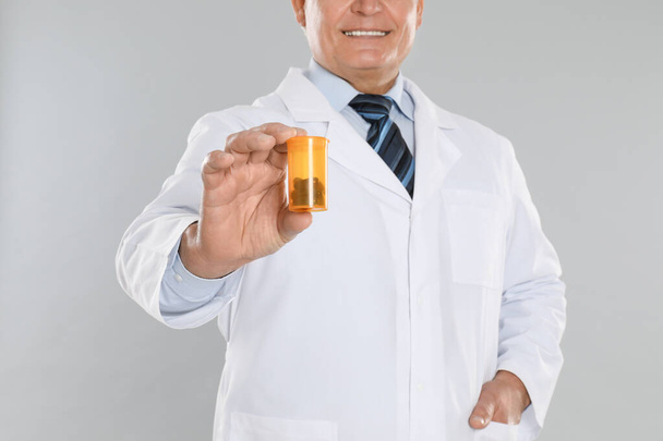 Senior pharmacist with pills on light grey background, closeup - Photo, Image
