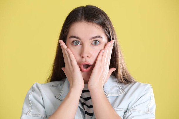 Portrait of surprised young woman on yellow background - 写真・画像