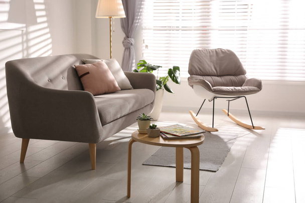 Stylish living room interior with comfortable sofa and rocking chair - Foto, afbeelding
