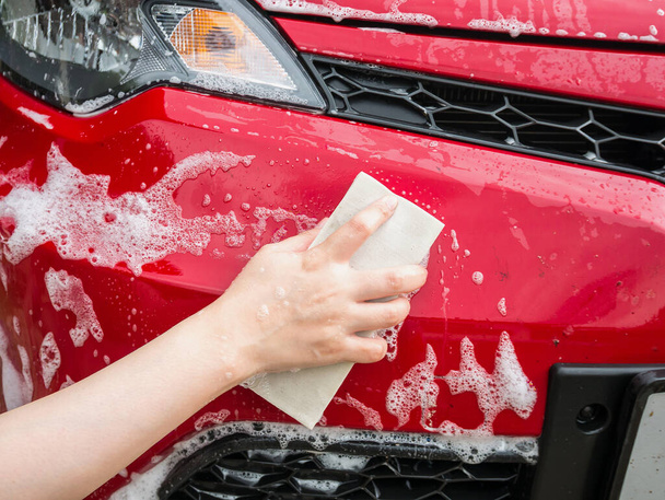 mano mantenga la esponja sobre el coche rojo para lavar - Foto, imagen