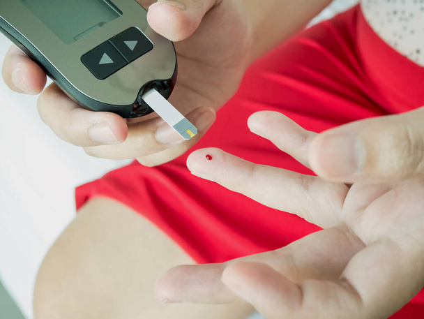 азиатка, измеряющая уровень глюкозы с помощью цифрового глюкозы, диабет - Фото, изображение