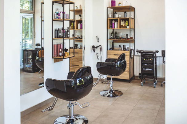 Workshop of hairdressers. Beauty salon with chairs, hair dryers, combs and mirrors. Interior of empty modern hair and beauty salon. Barbershop interior.  - Fotoğraf, Görsel