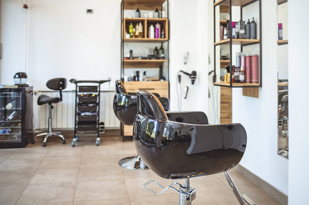 Horizontal shot of empty chairs in retro styled barbershop. Hair salon interior. Brand new and very clean european hair salon. Interior of empty modern hair and beauty salon decorated in wooden colors - Foto, imagen