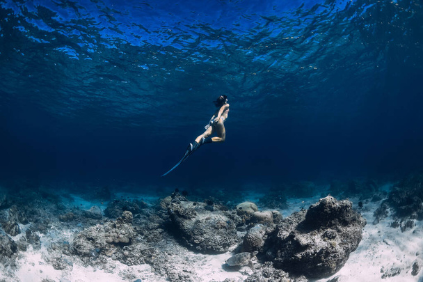 Woman freediver glides underwater in ocean. Freediving with fins - Φωτογραφία, εικόνα