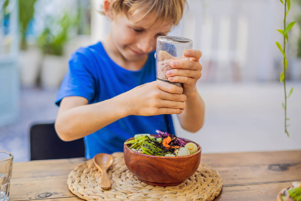 Мальчик ест миску с креветками, кукурузой, авокадо, имбирем и грибами - Фото, изображение