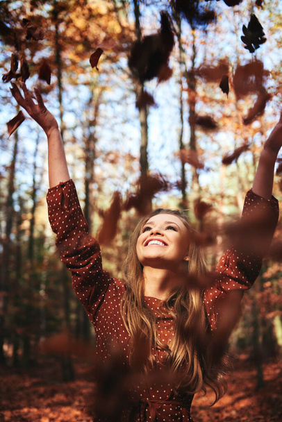 Glückliche schöne Frau wirft Herbstblätter in den Wald - Foto, Bild