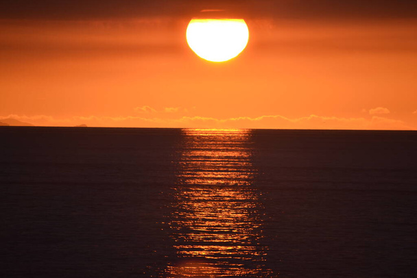 Zachód słońca nad Tapia de Casariego, w Asturii. Widzimy, jak słońce spada i chowa się nad morzem, aż zniknie.. - Zdjęcie, obraz