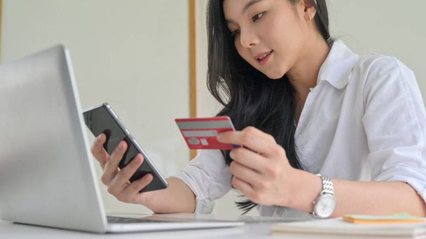 Young women are using smartphone and credit card with laptop. - Photo, Image