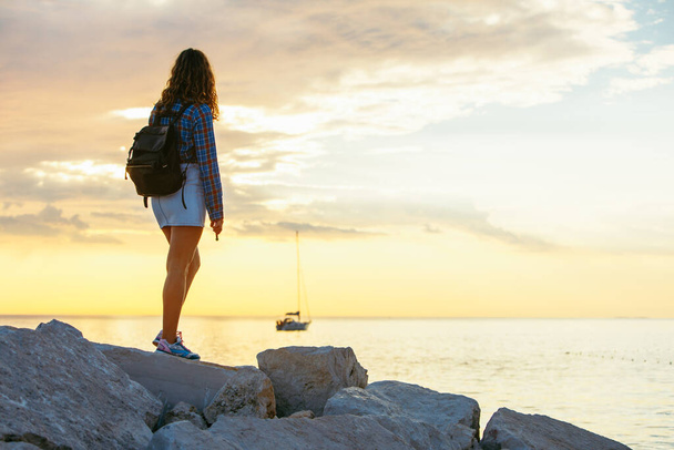 woman with backpack looking on sunset over the sea. copy space - Foto, Imagem