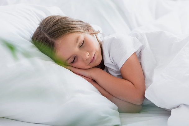 selective focus of girl sleeping while lying on white bedding - Photo, Image