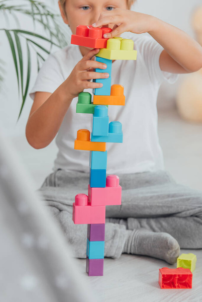 selective focus of boy playing with building blocks while sitting on floor in pajamas - Фото, зображення