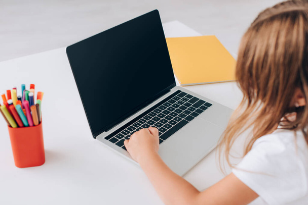 visão de alto ângulo da menina usando laptop com tela em branco perto do suporte da caneta e notebook
 - Foto, Imagem