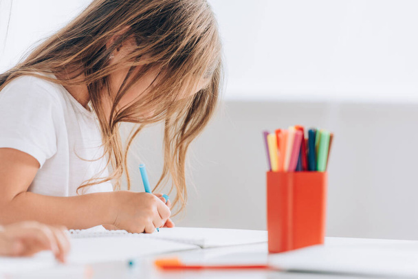 вибірковий фокус дівчини в білій футболці малюнок з фетровою ручкою, сидячи за столом
 - Фото, зображення