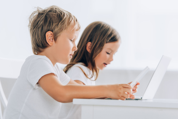 selective focus of concentrated boy and girl using laptops at home - Фото, изображение