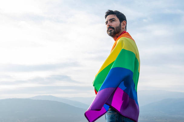 schöner Mann mit Homosexuell Flagge am Himmel Hintergrund. Konzept der Homosexuell, Stolz, Vielfalt - Foto, Bild