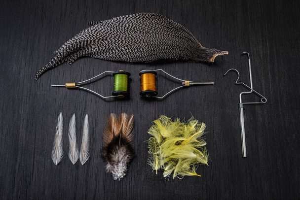 materials and tools for tying lures on a wooden table. hobby concept - Photo, Image