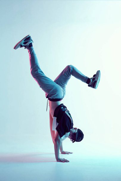 Cool young breakdancer guy stands on hands dancing hip-hop in neon light. Dance school poster - Foto, Imagen