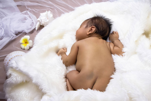 新生児は柔らかい白い絹のベルベットの上で眠って、周りのぼやけた光 - 写真・画像